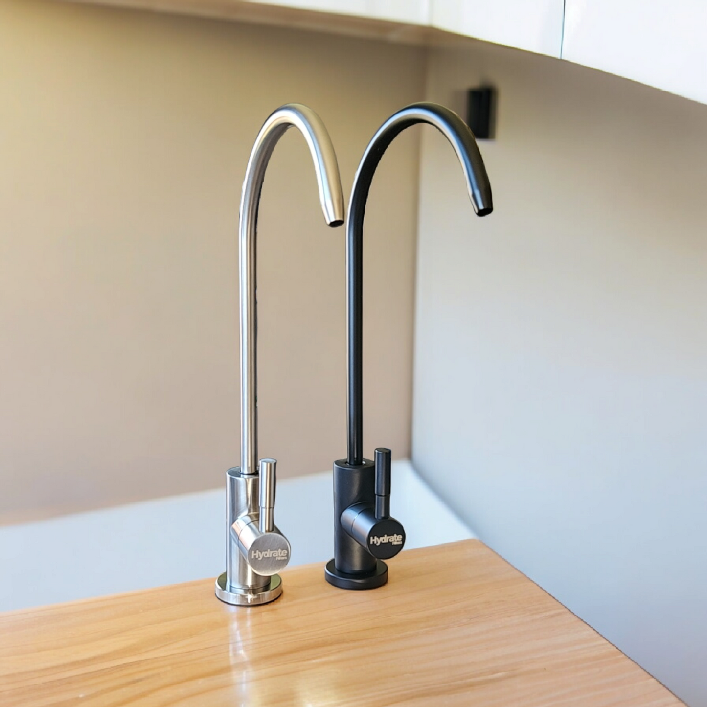 A black & silver stainless steel tap with a curved spout and a button handle, placed on a wooden surface.