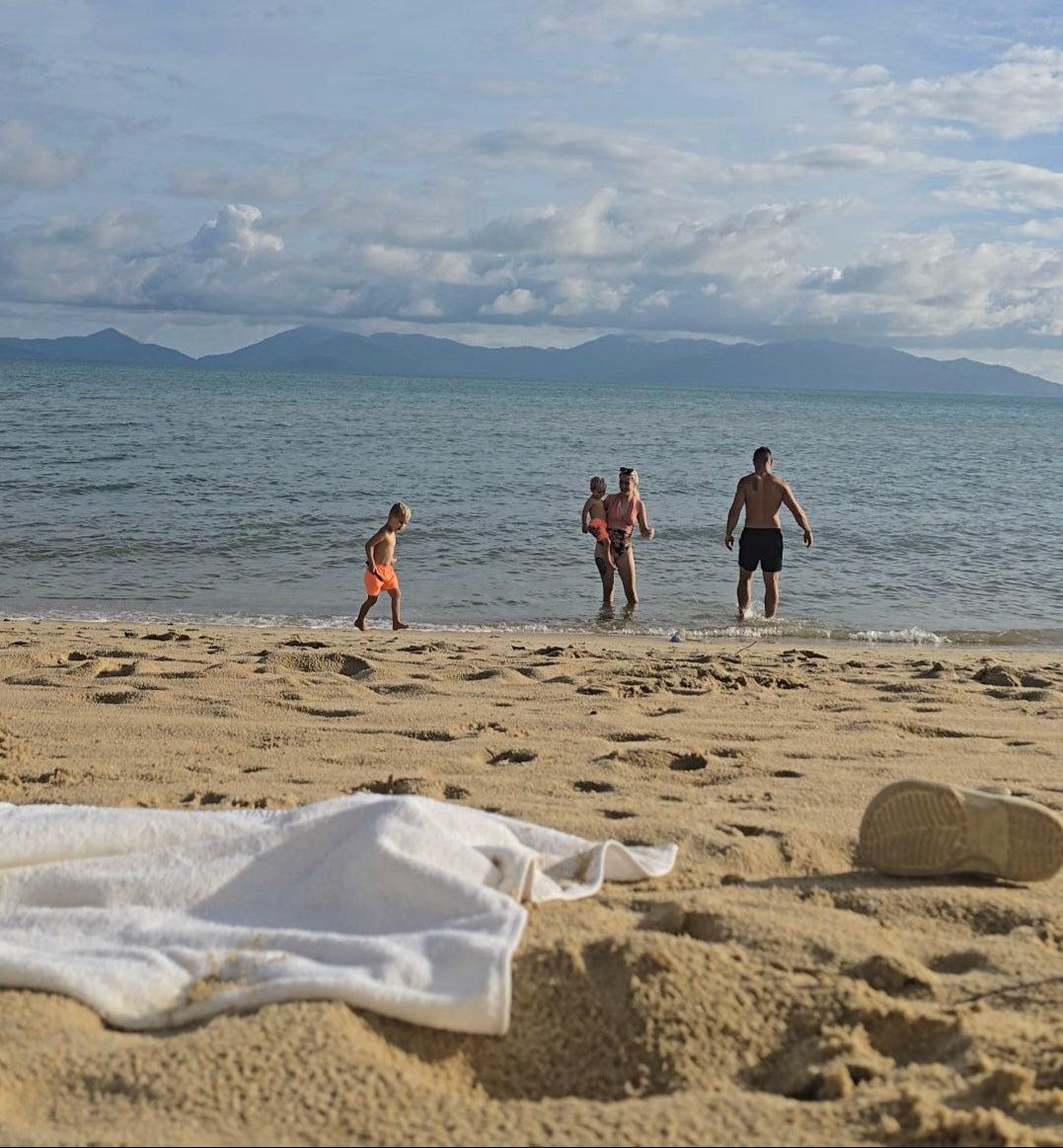 Three people on a beach with an island in the background